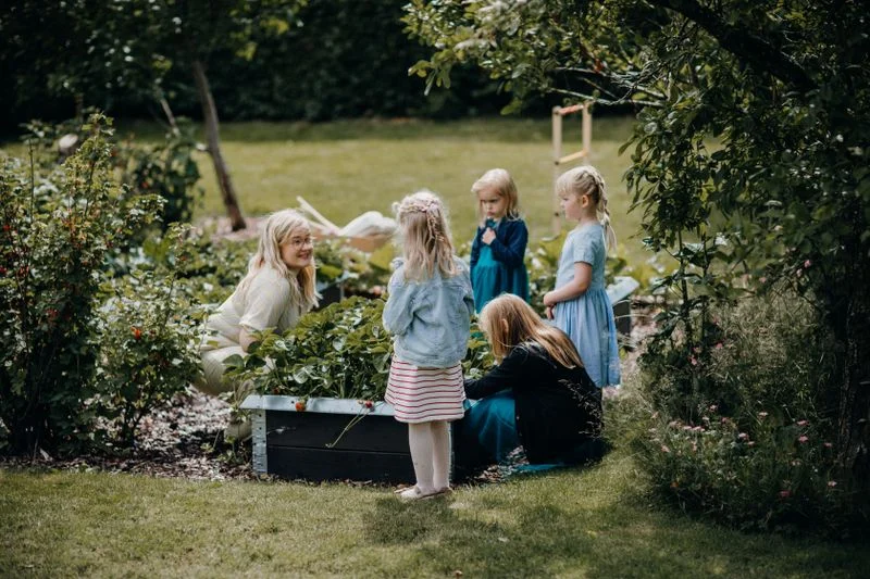 Children and an adult gardening together in a green plot